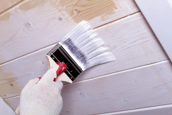 Gloved hand paint wooden ceiling linings in white