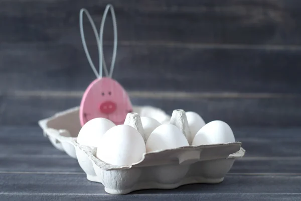 Carton of chicken eggs and the Easter bunny on a pink background