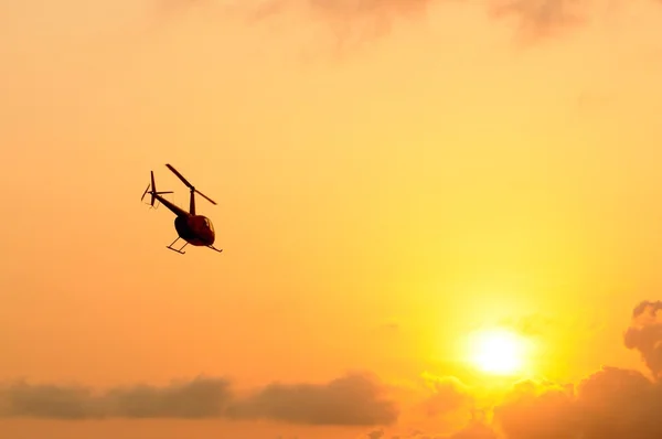 Helicopter in sky at sunset
