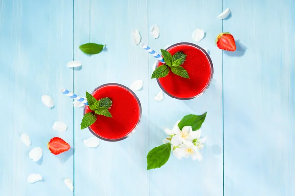 Strawberry smoothie and flower petals on blue background top vie