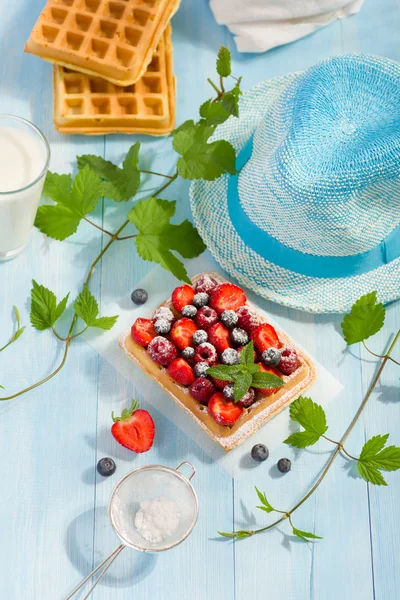 Waffles with strawberry and berry fruit on blue table top view