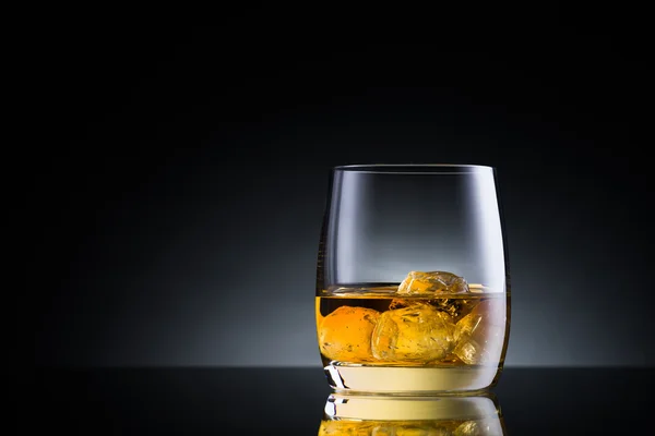 Whiskey glass on black glass surface