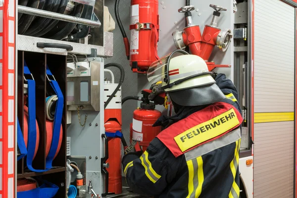 Firefighter in action and gets a fire extinguisher from the emergency vehicle