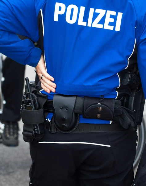 Police officer from behind with radio and weapon