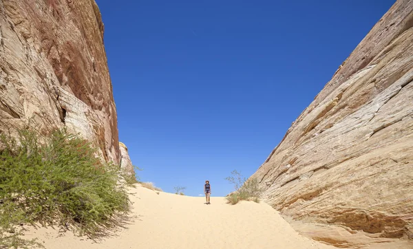 Young woman walking on sand between great rock formations, USA.