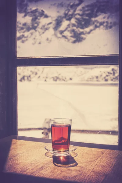 Retro old film style glass of hot tea on wooden table.