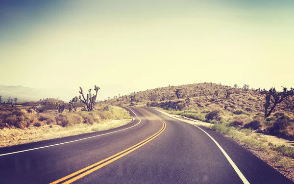 Vintage toned desert road seen through windshield.