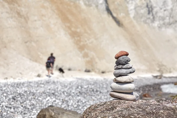 Stack of stones and blurred people with dog.