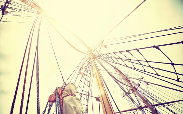 Vintage toned sailing mast against sun.