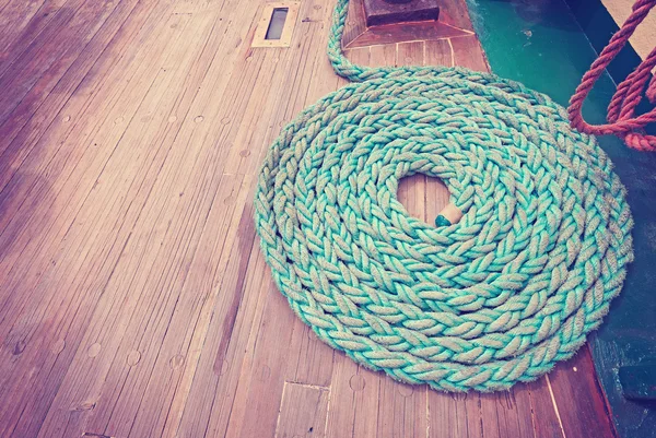Vintage toned mooring rope on wooden deck.