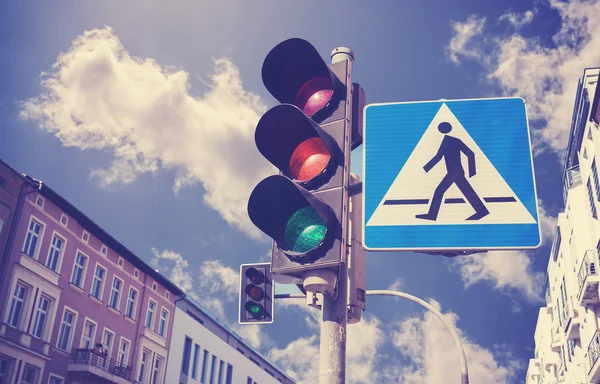 Retro filtered photo of traffic lights and pedestrian crossing sign.