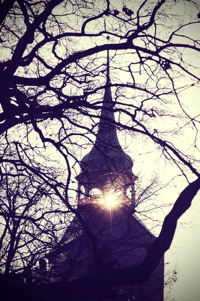 Vintage mysterious or scary church tower silhouette at sunset.