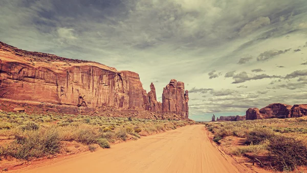 Vintage style photo of sandy road in Monument Valley, USA.