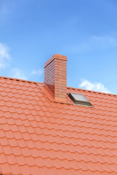 Roof with ceramic tile chimney against blue sky, space for text.