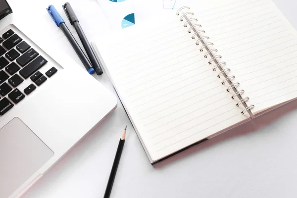 Blank note book with pencil pen and laptop on white table concep