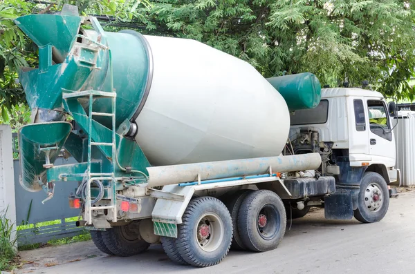 Concrete mixer truck with green cab over trees