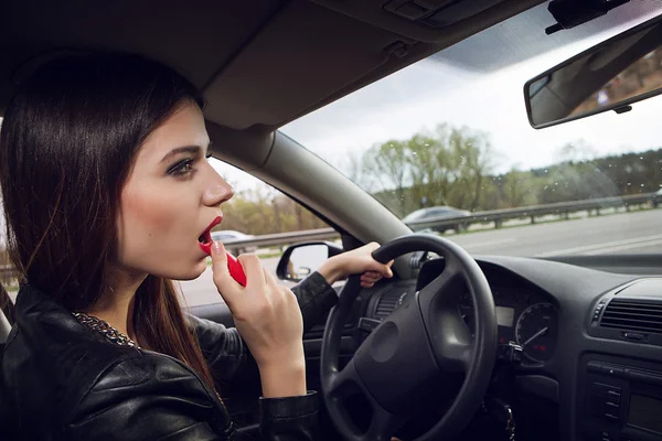 Painted woman lipstick while driving