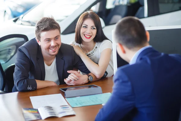 Car salesman giving key of  new car to  young  owners