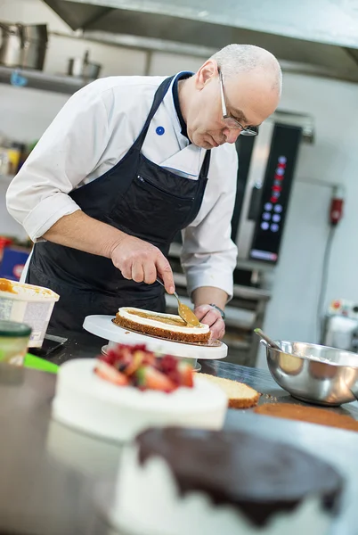 Baker prepares a cake and eclairs