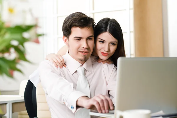 Happy young relaxed couple working on laptop computer