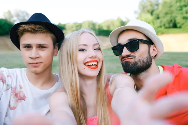 Outdoor portrait of group of friends taking photos with a smartphone in the park