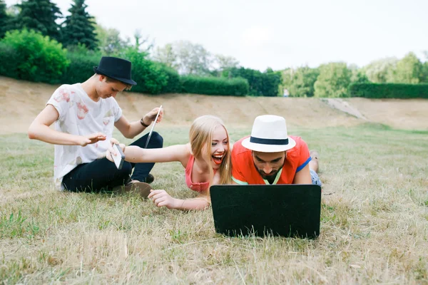 Technology and people concept - group  friends with tablet pc computers , smartphone sitting  in park