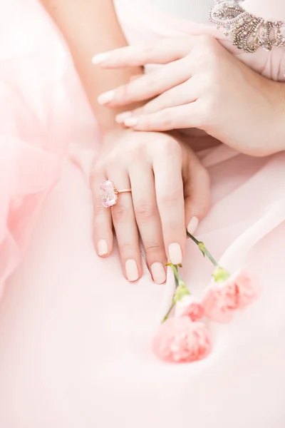 Pink Carnation flower in the hands of a girl on a pink background.