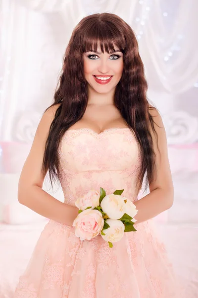 Beautiful young bride in the peach, wedding dress. The gentle light bedroom.Wedding in pink.
