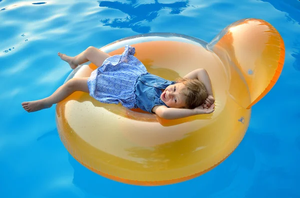 Little girl swimming in the pool on an inflatable chair, bright