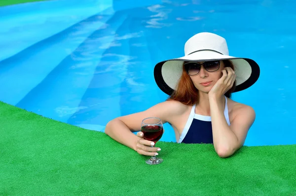 Beautiful woman in a hat and sunglasses in the pool.