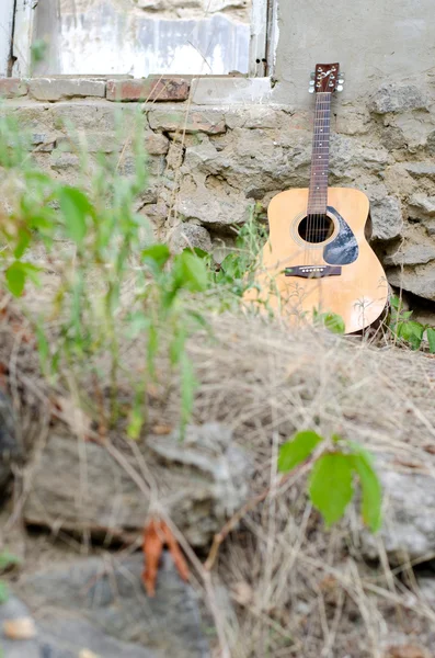 Acoustic guitar leaning against the wall