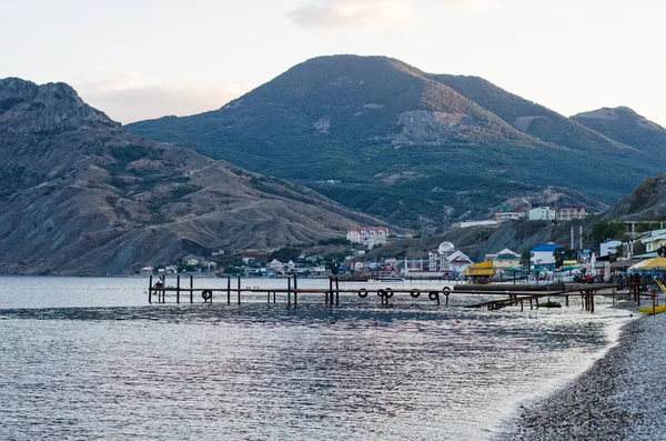 Sea coast, high mountains and a wooden pier