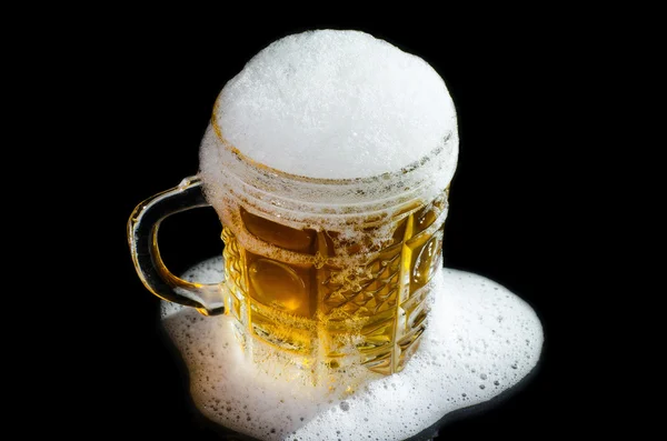 Beer mug with froth close-up over black background.