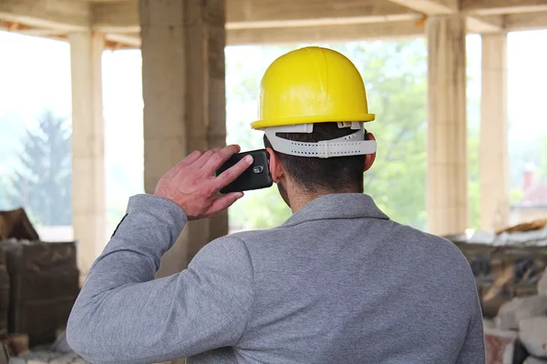 Engineer at a construction site making a business call