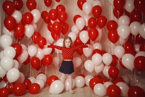 Happy little girl with red and white balloons