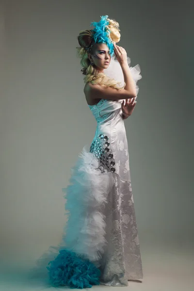 Studio shoot of woman with creative hairstyle, makeup and dress.