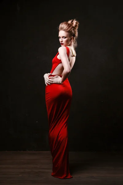 Studio shoot of posing woman in long red dress. Retro style.