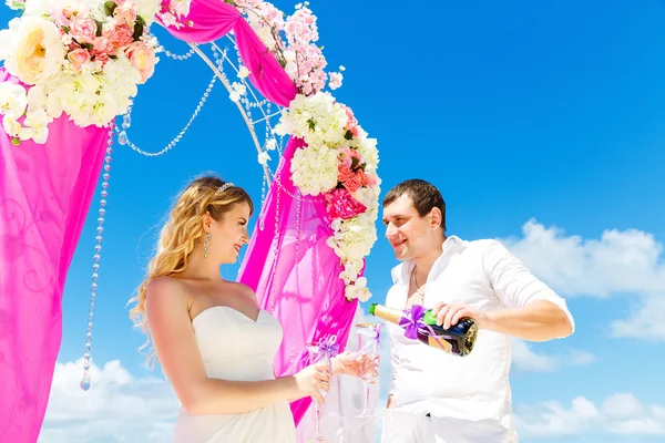 Wedding ceremony on a tropical beach in purple. Happy groom and