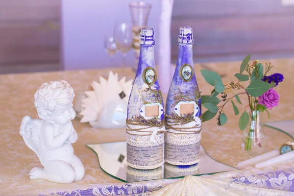 Decoration for wedding table in purple color . Bottle of champag