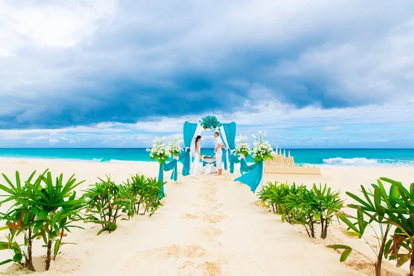 Wedding ceremony on a tropical beach in blue. Happy groom and br