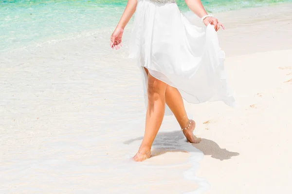 Beautiful young bride in a white wedding dress walking on a trop