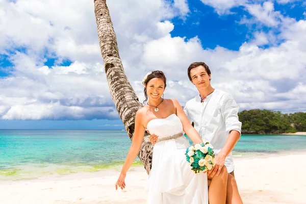 Happy groom and bride having fun on the sandy tropical beach. We