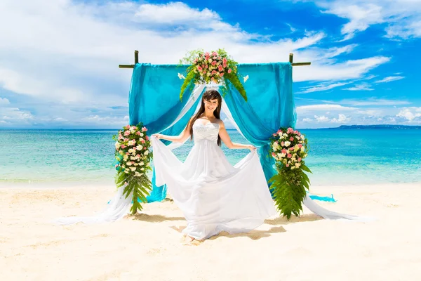 Wedding ceremony on a tropical beach. Happy bride under the wedd
