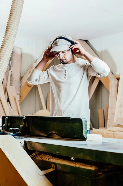 Carpenter working cutting some boards, he is wearing safety glasses and hearing protection