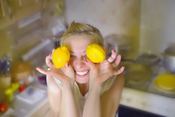 Girl holding lemons in the kitchen around the eyes smiling