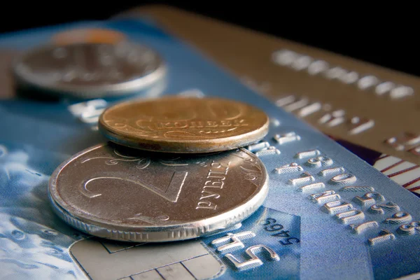 Coins lie on cash cards against a dark background.