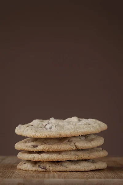 Stack of chocolate chip cookies with nuts on cutting board