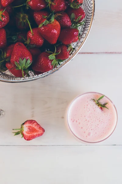 Strawberries and strawberry milk shake on a white vintage wooden
