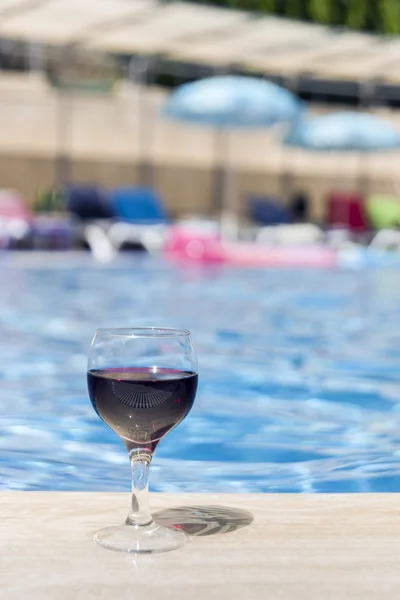 Full wine glass near the pools edge.