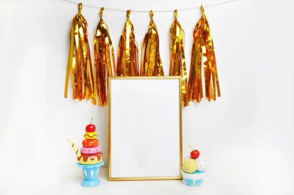 Frame mockup .Gold frame and white wall. Gold tassel and sweet bar. Ice cream, cupcakes, cherry. Gold stapler. Place your work, print art, white background.